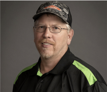 a man in front of a green SERVPRO truck